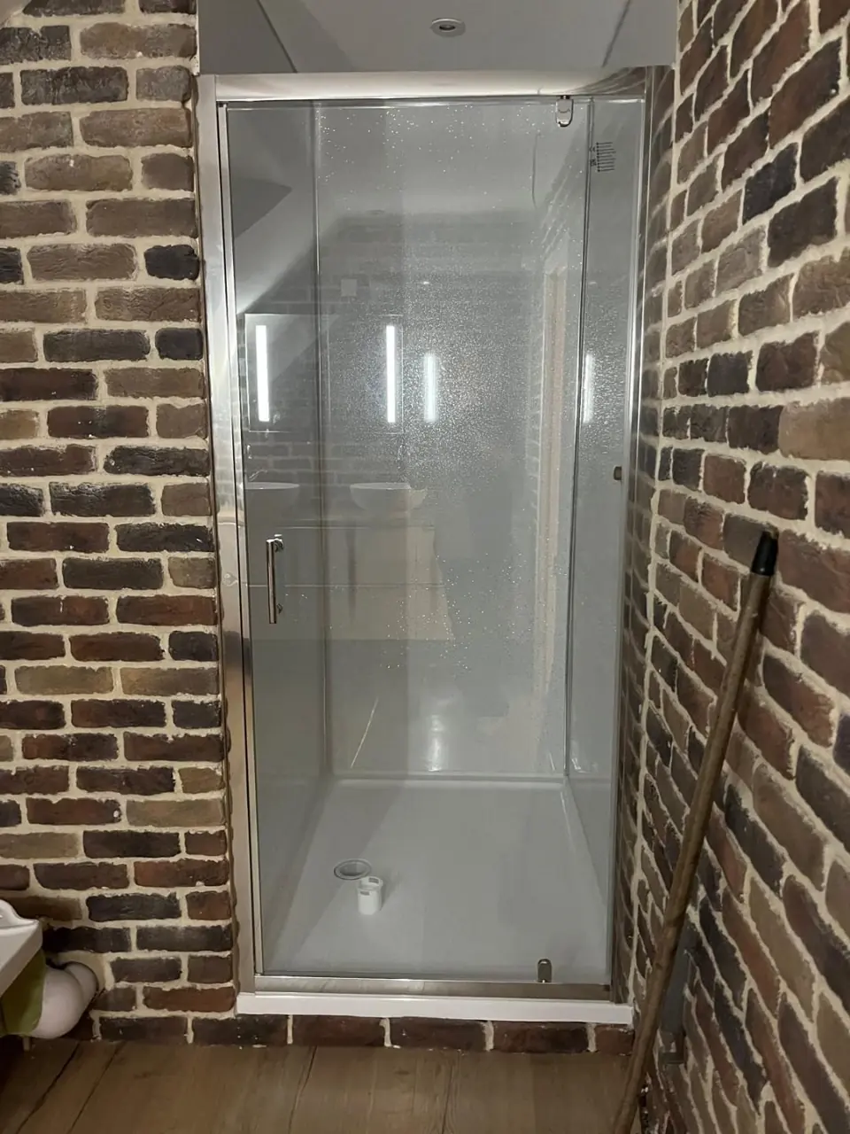 Glazed shower installed against the brick feature wall