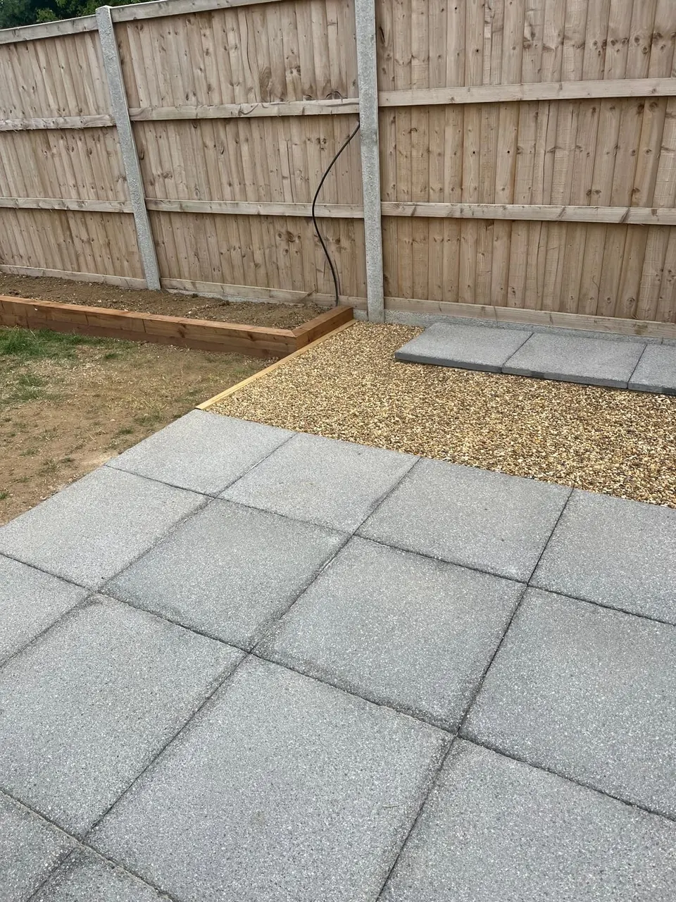 Grey paving and timber-edged border during installation