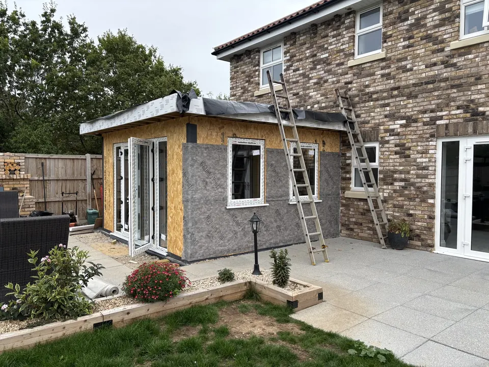 Timber extension with white-framed doors and windows fitted to the sheathed walls