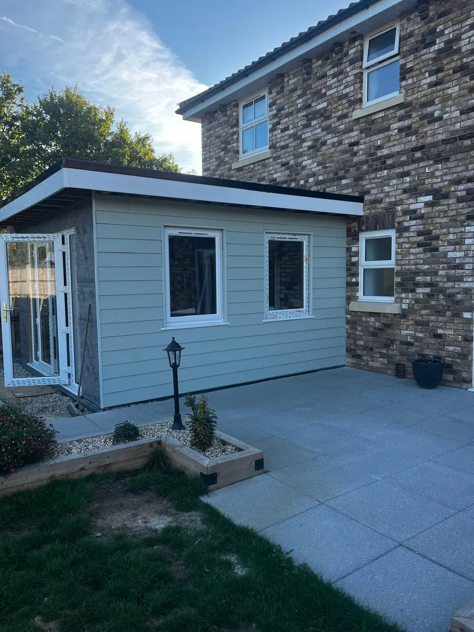 Grey horizontal cladding fitted around two windows while the adjoining wall remains unfinished