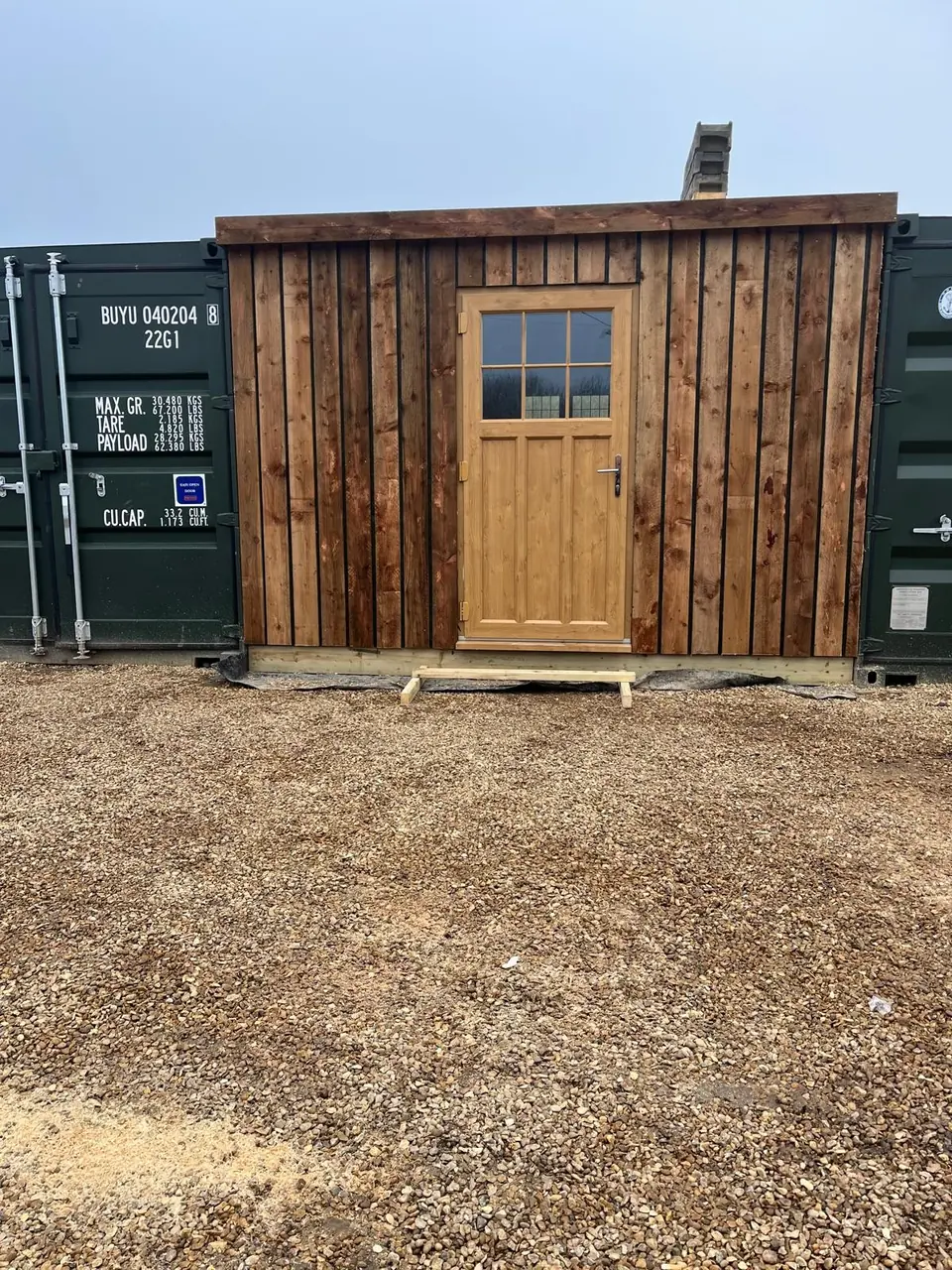 Completed timber-clad frontage and glazed door fitted between two shipping containers
