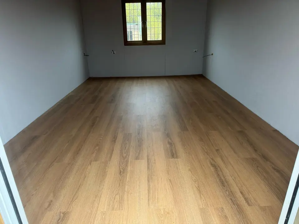 Finished room with white walls, rear window and wood-effect flooring