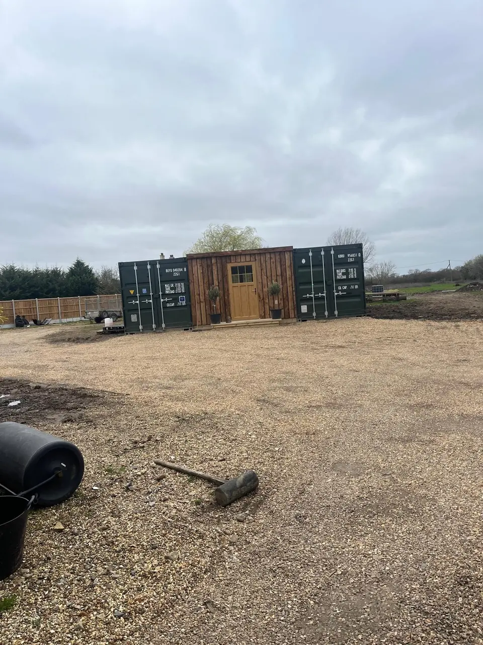 Wide view of the completed timber-clad room between two shipping containers