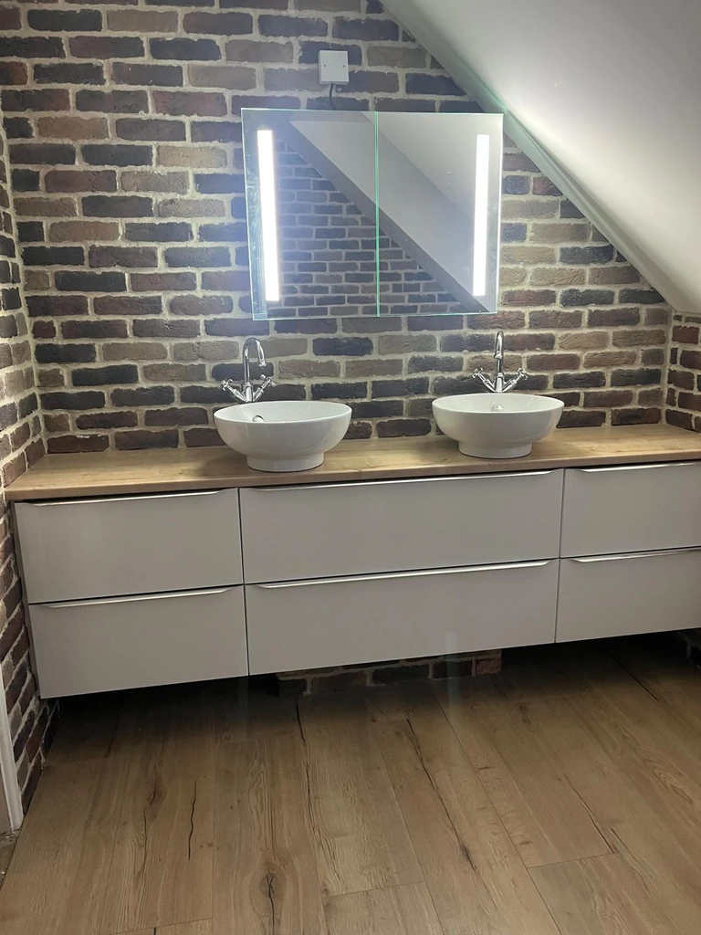 Double vanity with two vessel basins against a brick feature wall