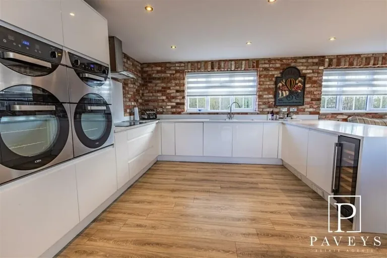 Completed garage conversion with white cabinetry, brick-slip walls and timber-effect flooring