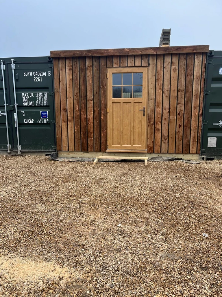 Completed timber-clad frontage and glazed door fitted between two containers